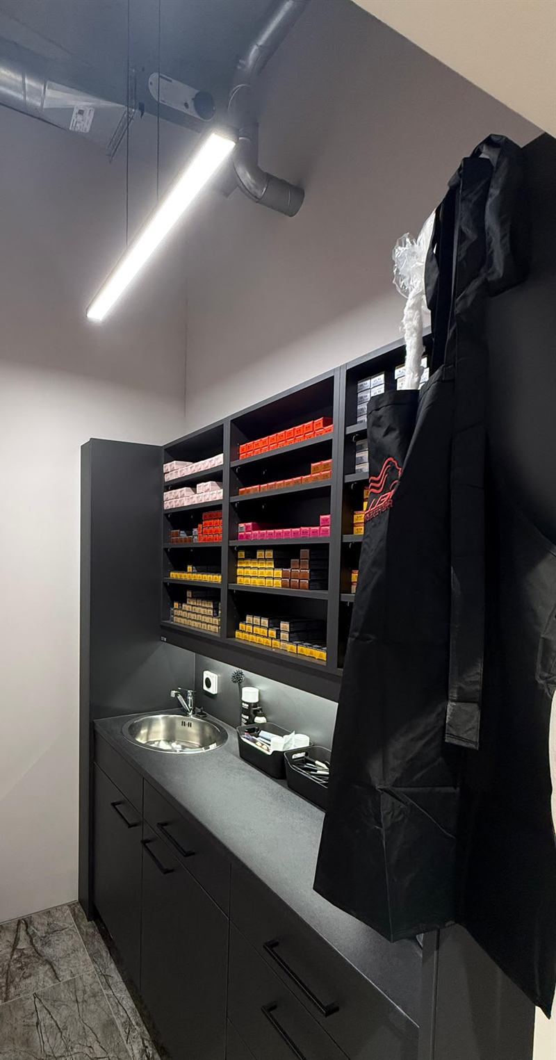 Farbraum mit Lichtleiste über der Arbeitsfläche, Spüle und Regal mit sortierten Farbtuben